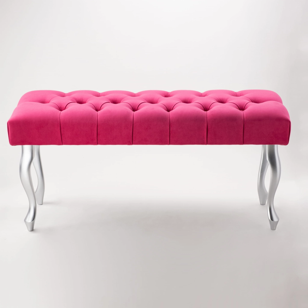 An elegant, quilted bench in an intense fuchsia color with silver legs.