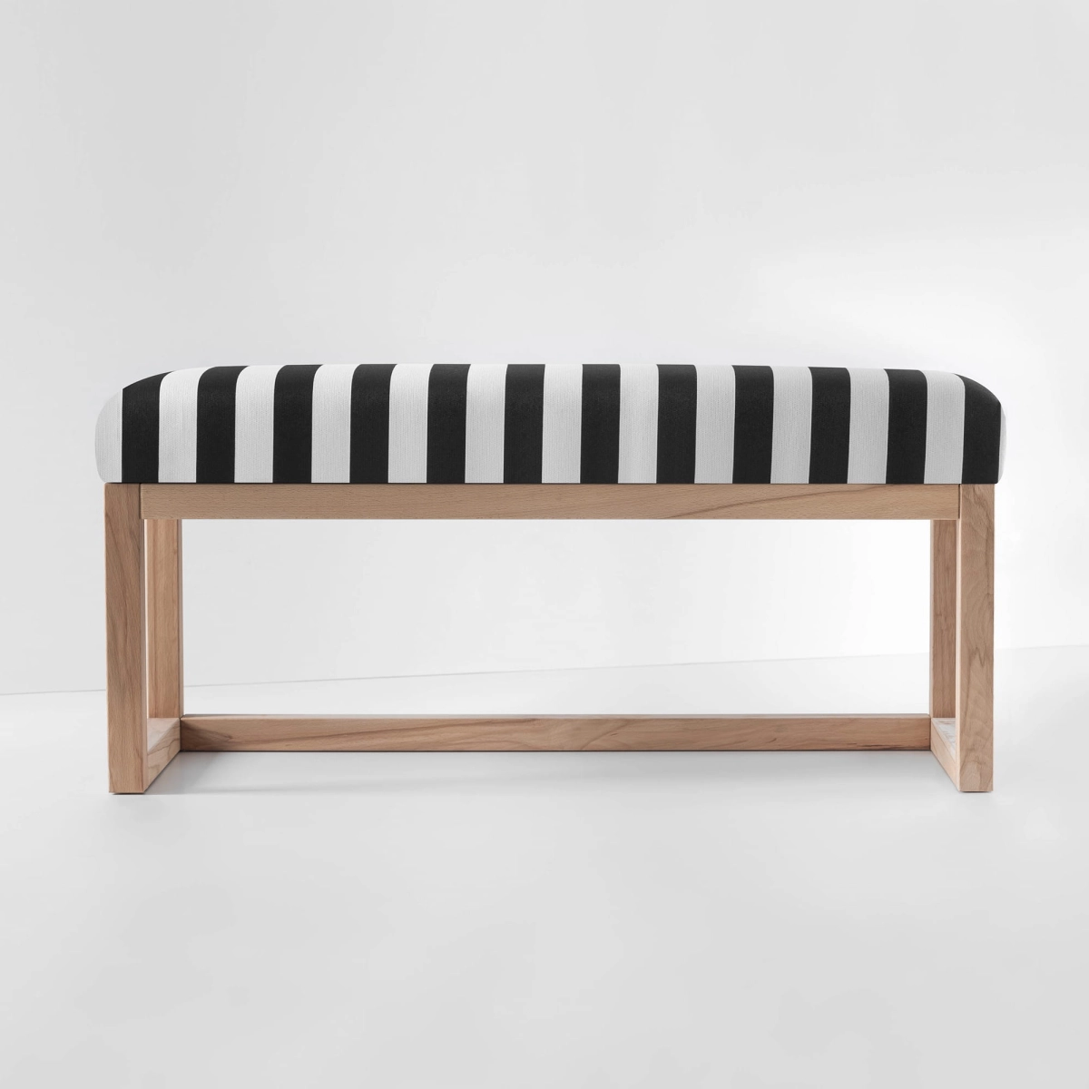 Upholstered bench in black and white stripes with one shelf and light wood frame