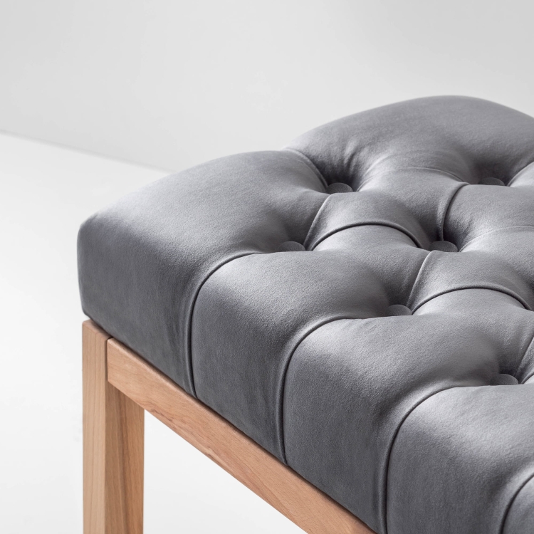 Quilted grey upholstered bench with wooden frame and lower shelf