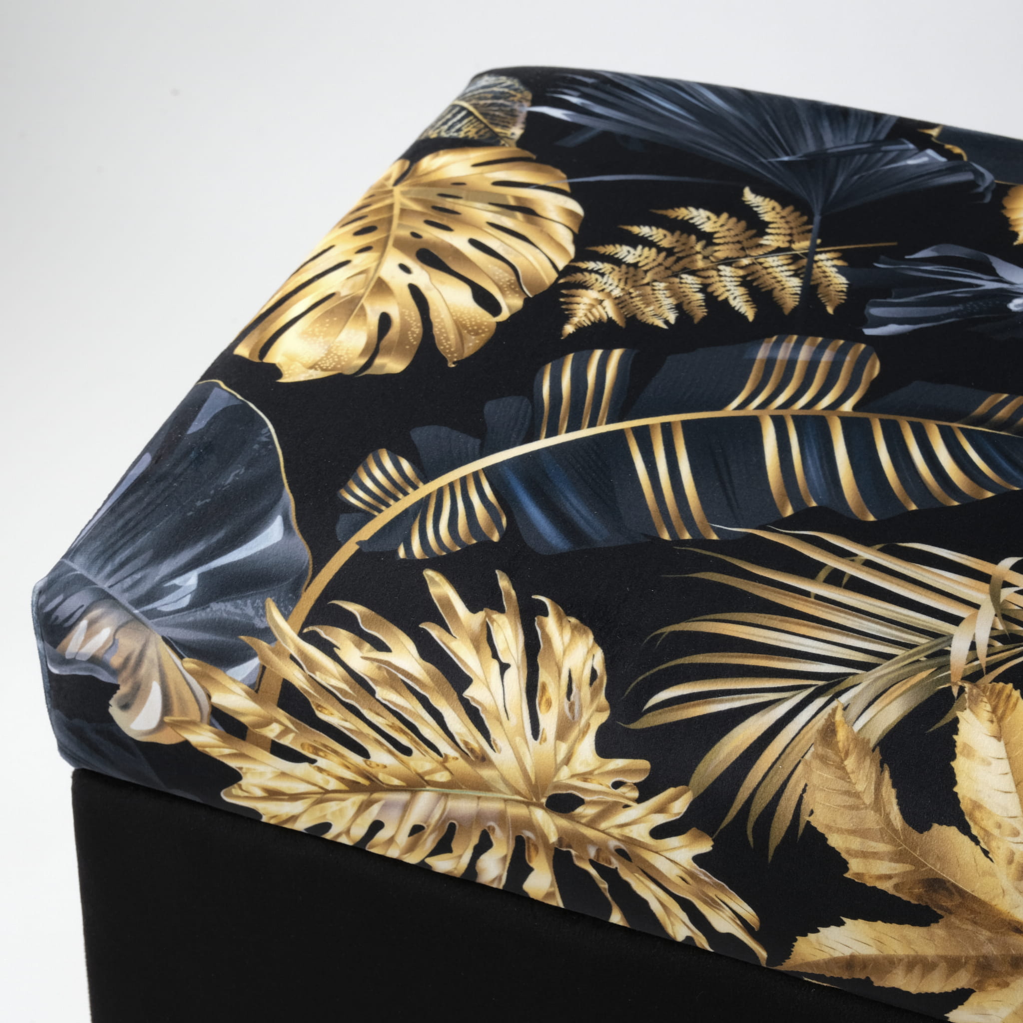Black quilted pouffe with gold leaf storage, elegant on gold legs