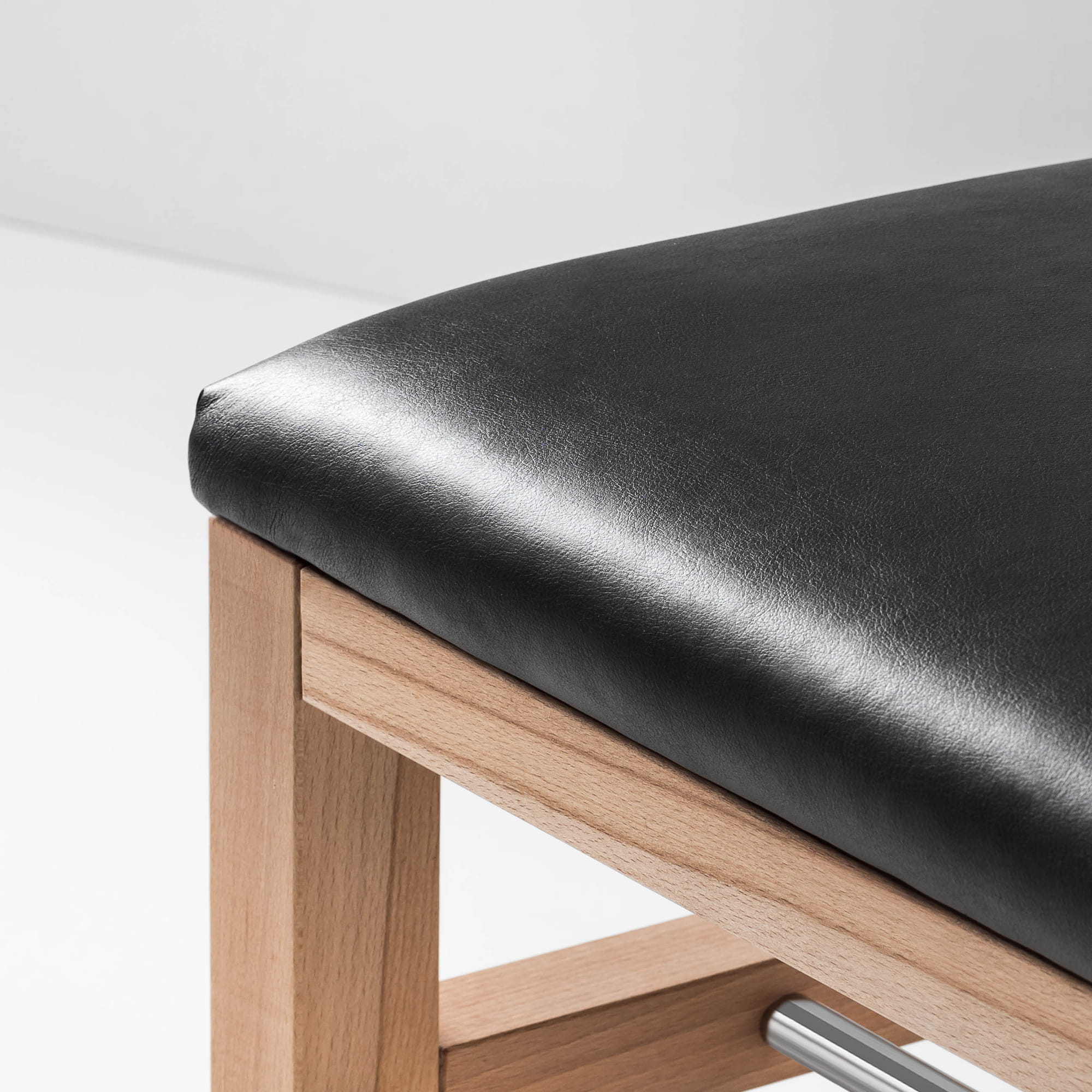 Stylish hall bench with black upholstery, wooden frame and metal crossbars for shoes